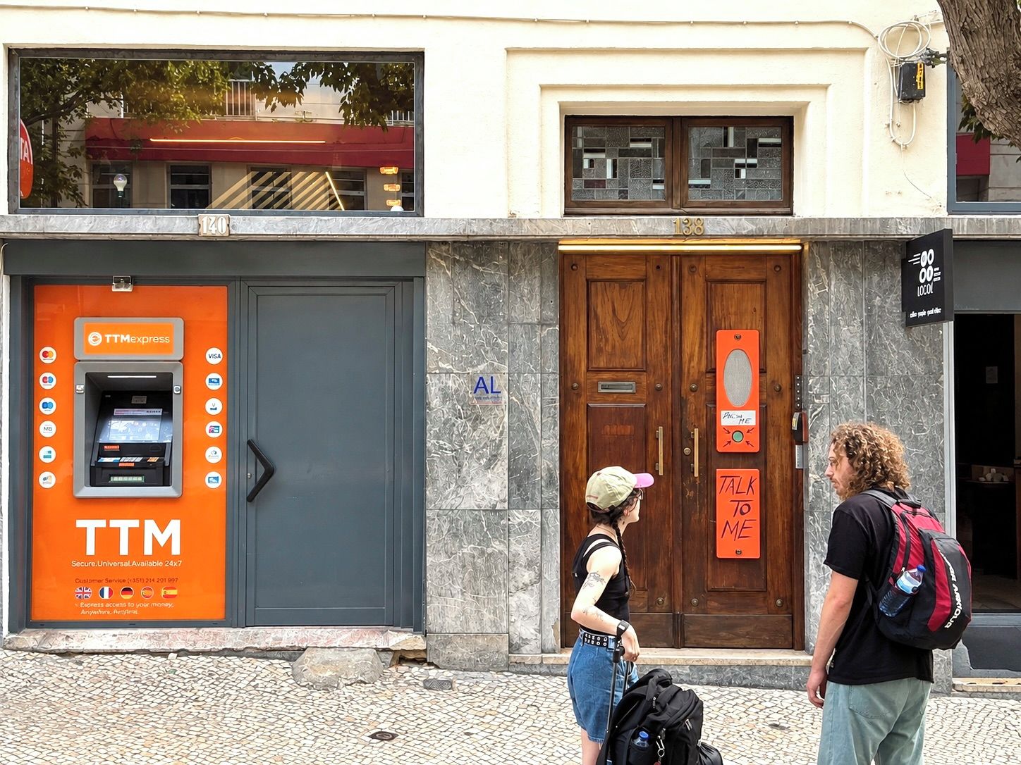 Un escaparate con un cajero automático TTM Express, una puerta de madera y un letrero que dice 'TALK TO ME'.