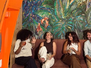 A group of people sitting on a couch with a colorful tropical mural in the background. - Avenue Rooms & Suites - Hostel (Lisbon)