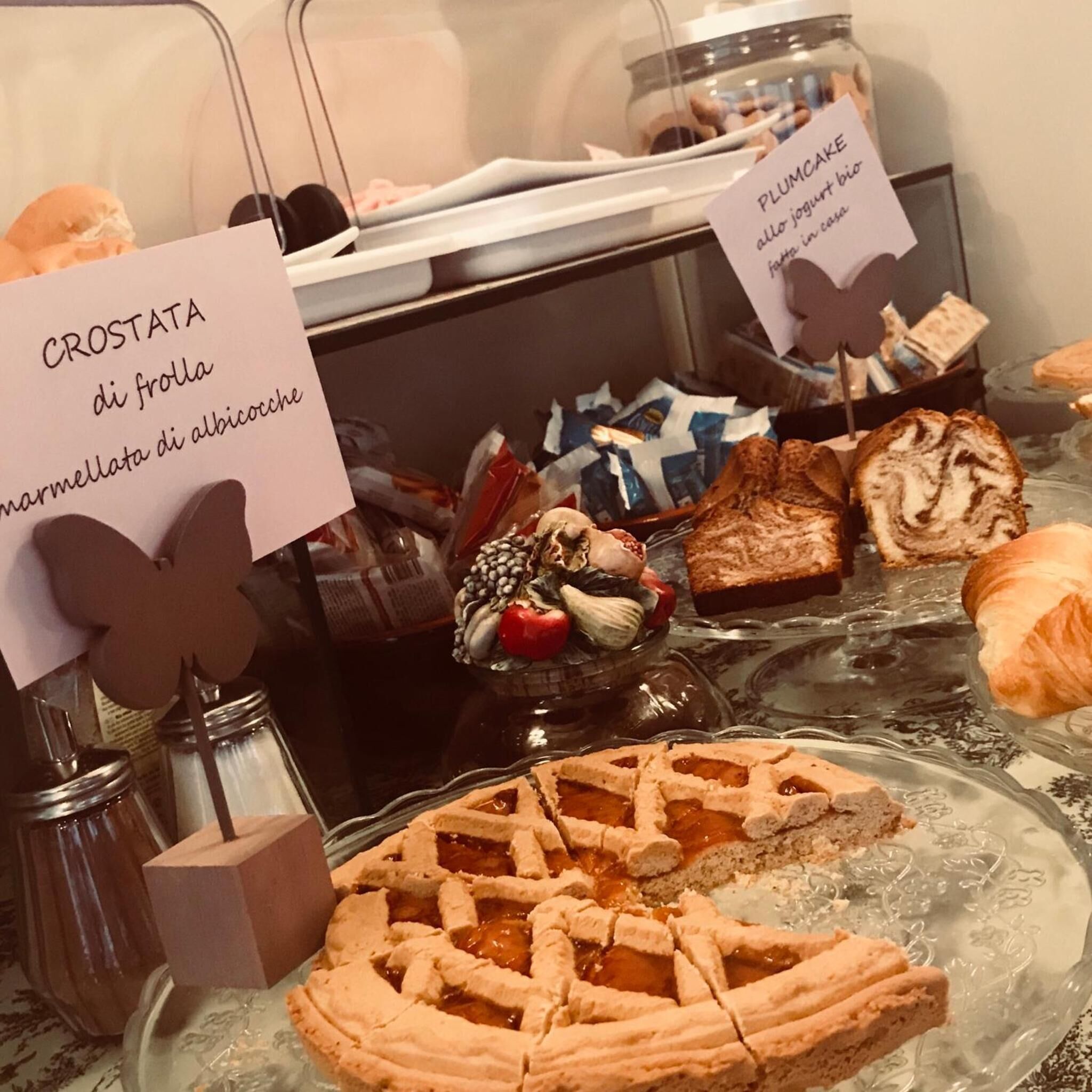 Een presentatie van gebak en desserts, met labels die soorten aangeven zoals crostata en plumcake.
