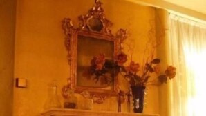 A room with a fireplace, a mirror, and a vase with flowers. - Hotel Al Sole - Preganziol (Preganziol)