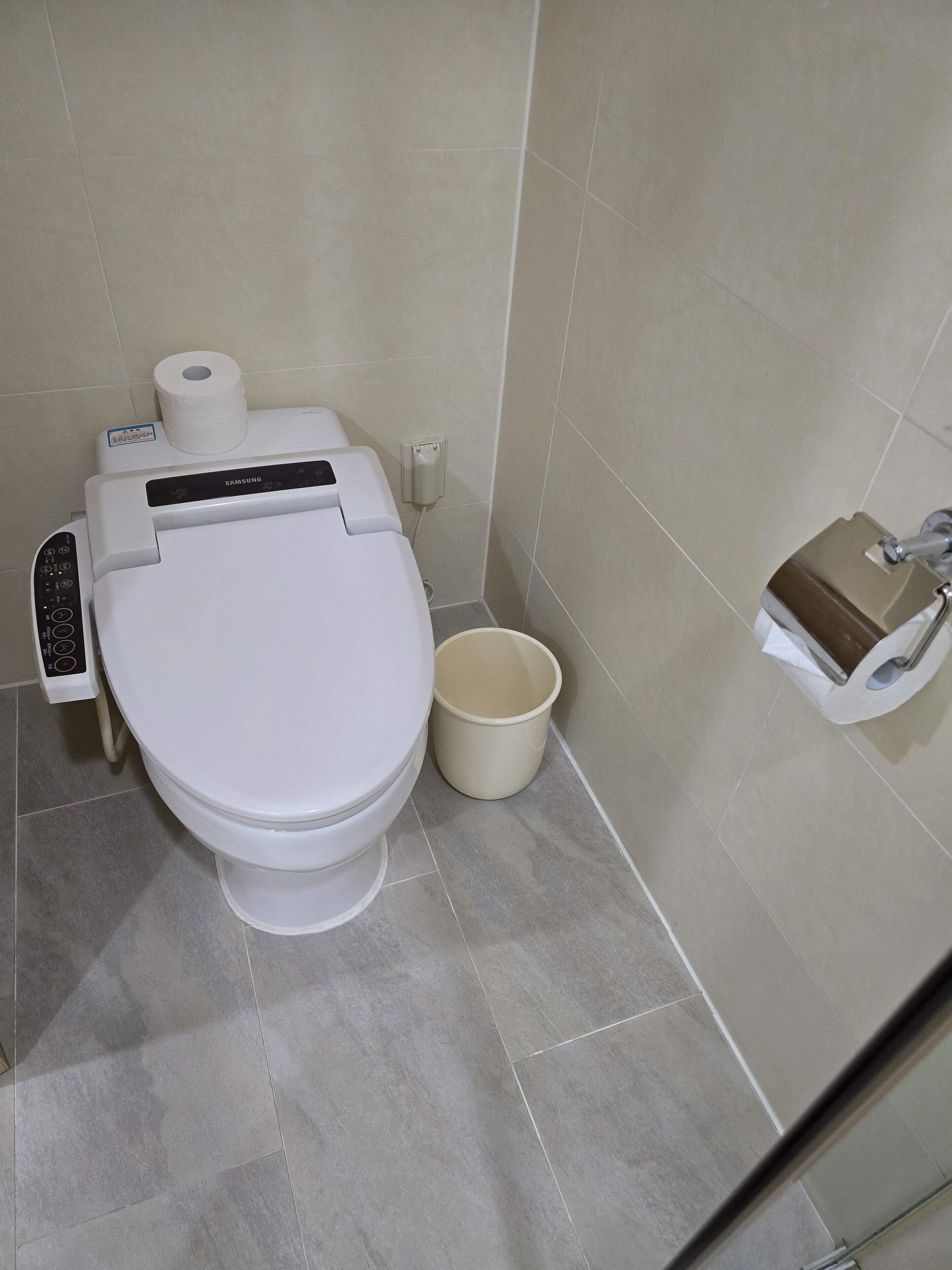 Et moderne toilet med kontrolpanel, toiletpapirholder og bidét.