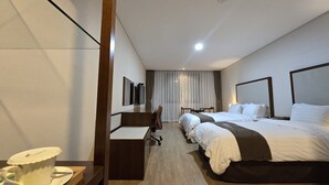 Ein Hotelzimmer mit zwei Betten, einem Schreibtisch, einem Stuhl, einer Kaffeetasse und einem Fernseher.