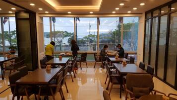 A modern dining area with large windows, wooden tables, and chairs.