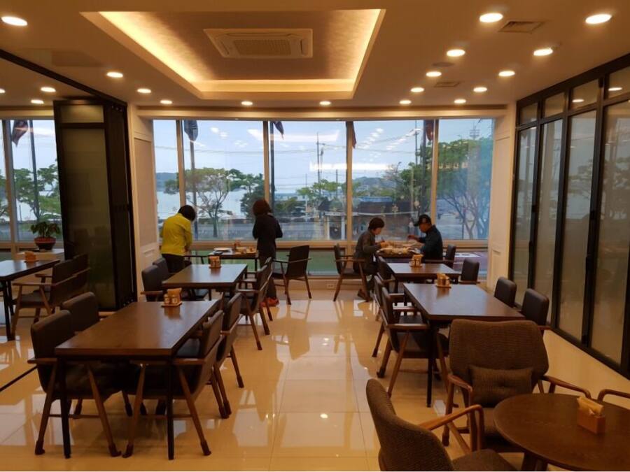 A modern dining area with large windows, wooden tables, and chairs.