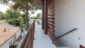Una escalera con barandilla de madera que lleva a un balcón con vista a un estacionamiento y edificios.