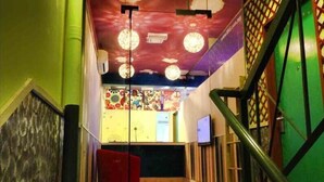 Eine Treppe mit Schachbrettmuster führt zu einem Raum, der mit einem farbenfrohen Wandgemälde und einem Schreibtisch gestaltet ist.