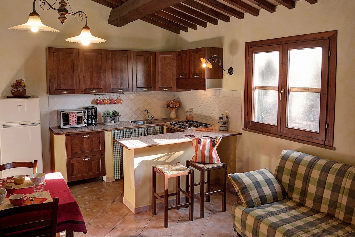 A compact kitchen with wooden cabinets, a built-in stove, and a dining area with a table and chairs.