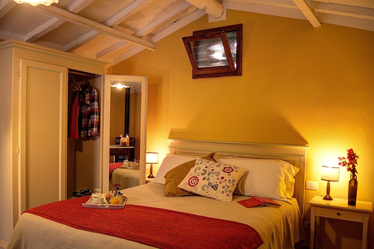 A hotel room with a bed, bedside tables, a mirror, and a wardrobe.