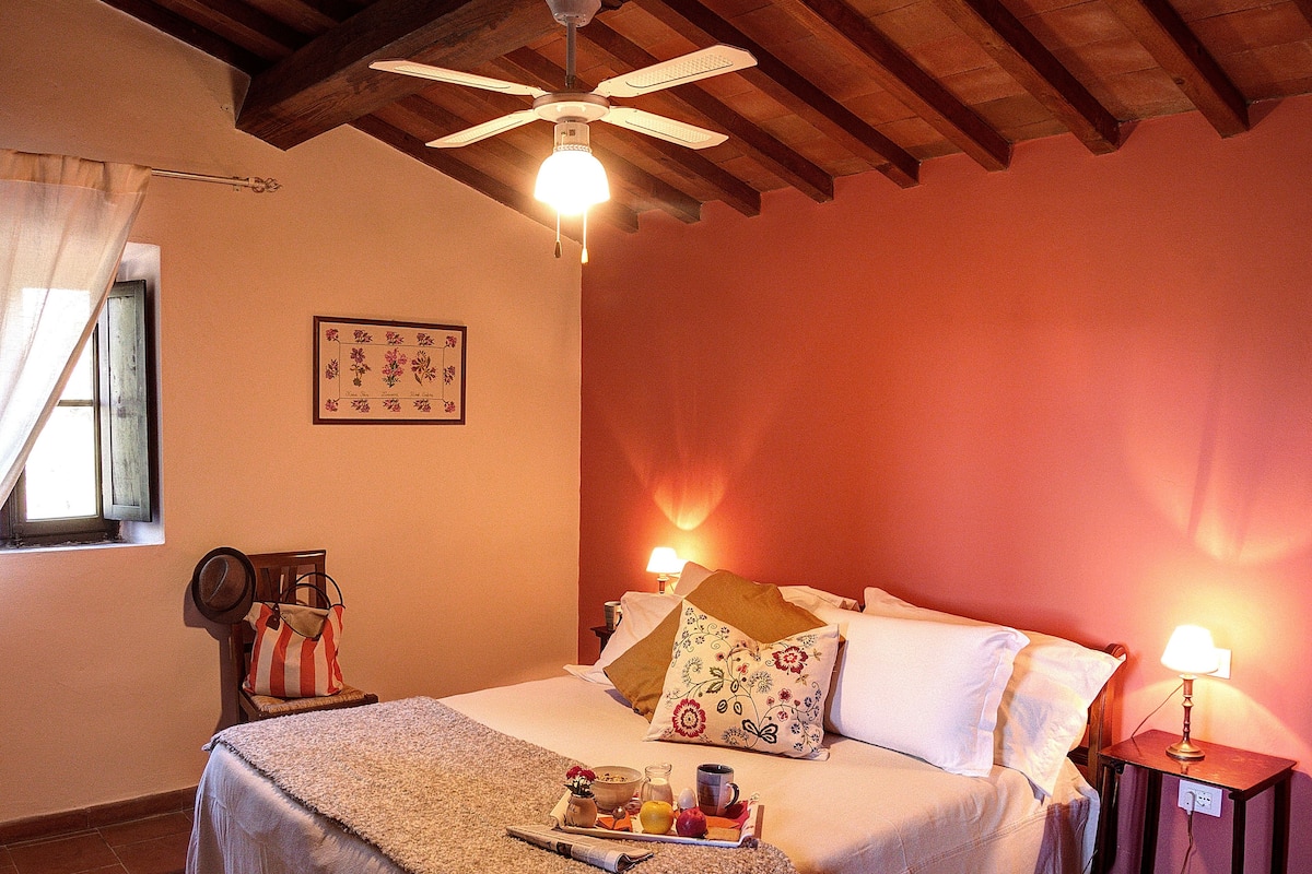 A bedroom with a bed, bedside tables, a ceiling fan, and a window with curtains.