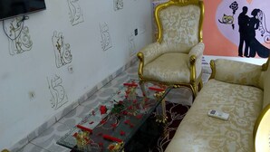 Een kamer met een patroon op de muur, een bank, een stoel en een tafel met rode en gouden decoraties.