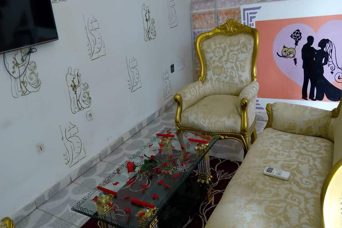 Een kamer met een patroon op de muur, een bank, een stoel en een tafel met rode en gouden decoraties.
