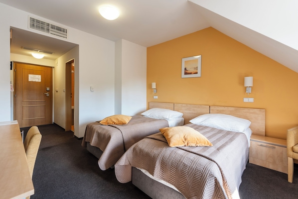 A hotel room with two beds, a desk, and a chair. - Hotel Chvalska Tvrz (Prague)