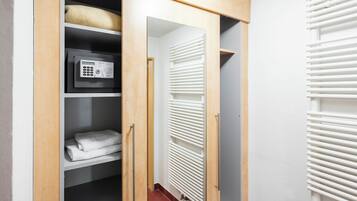 A walk-in closet with a built-in safe, a radiator, and neatly folded towels.