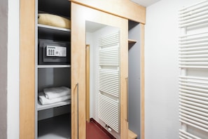 A walk-in closet with a built-in safe, a radiator, and neatly folded towels. - Hotel Chvalska Tvrz (Prague)