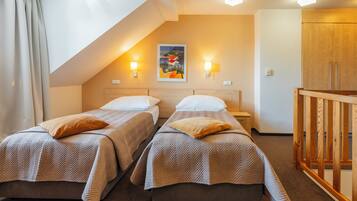 Een hotelkamer met twee bedden, een houten garderobe en een schilderij aan de muur.