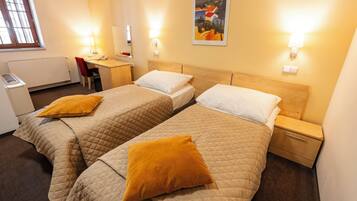 Hotellihuone, jossa on kaksi sänkyä, työpöytä ja tuoli.