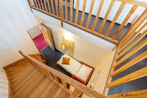 A high-angle view of a hotel room with a bed, a nightstand, a lamp, and a view of the hallway. - Hotel Chvalska Tvrz (Prague)