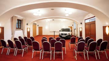 A conference room with a red carpet, rows of chairs, a white van, and wooden doors.
