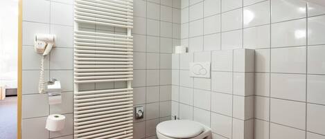A bathroom with a toilet, a towel rack, a hand dryer, and a toilet paper holder.