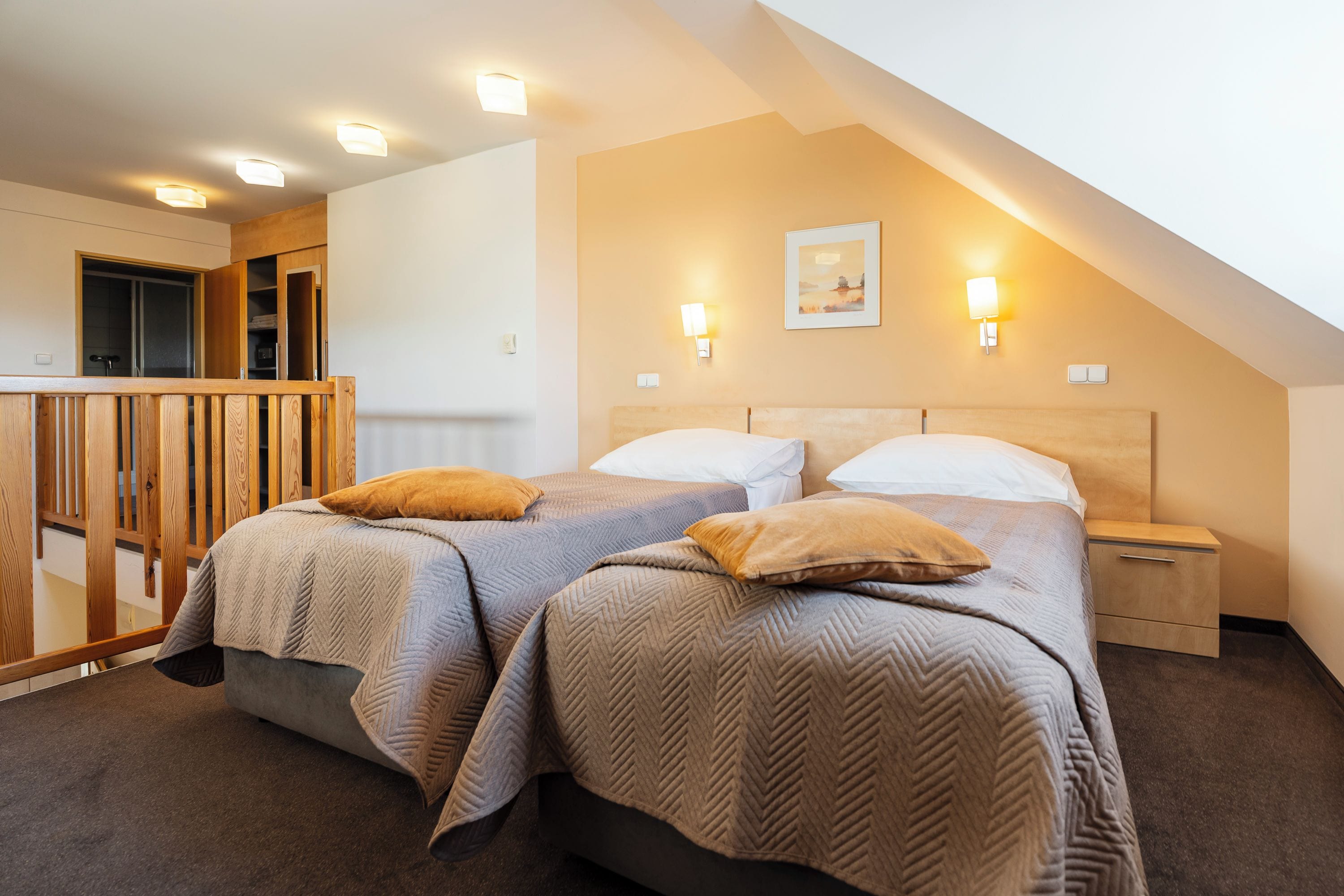 A bedroom with two beds, a wooden wardrobe, and a small desk.