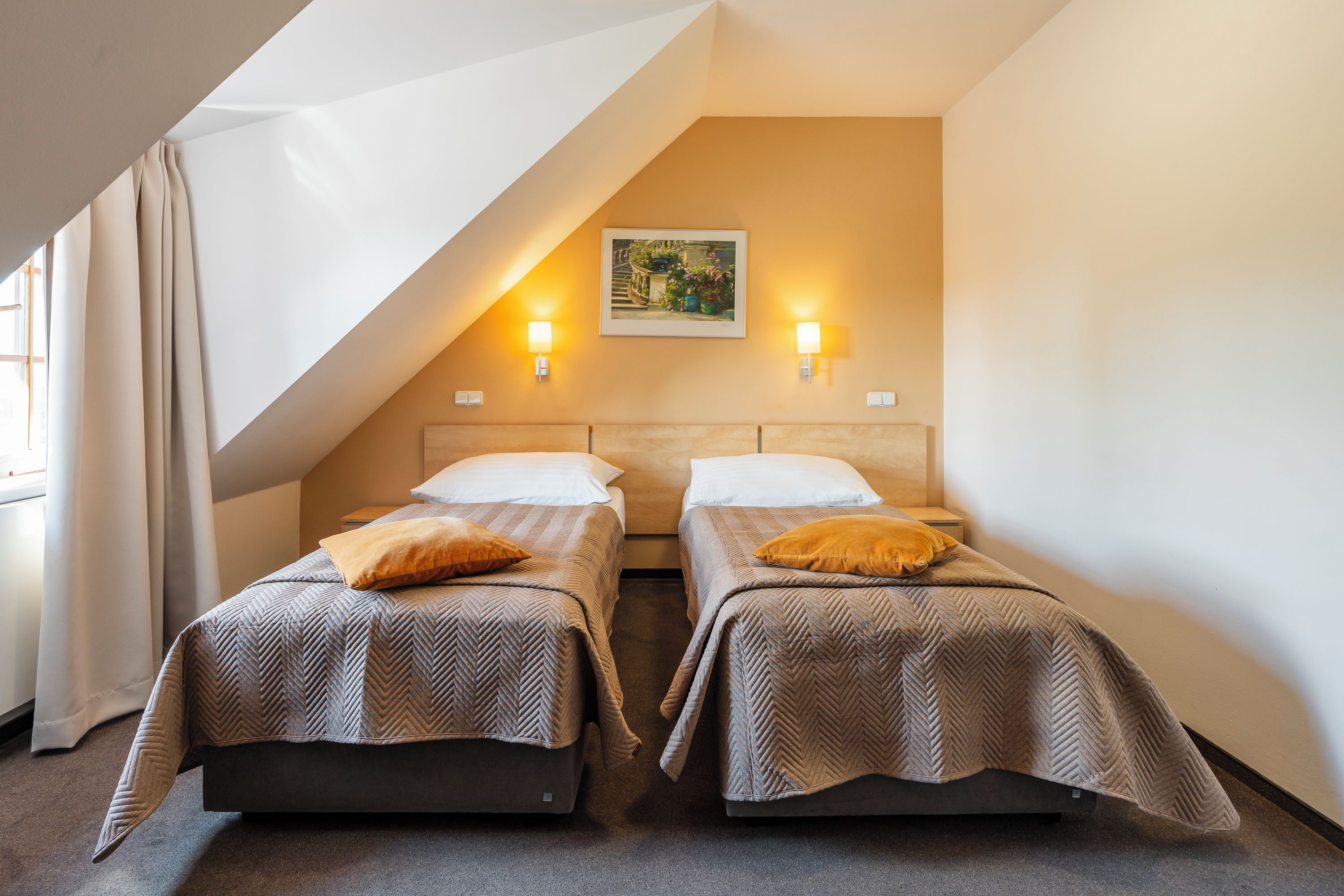 Een hotelkamer met twee bedden, een schilderij aan de muur en twee wandlampen.