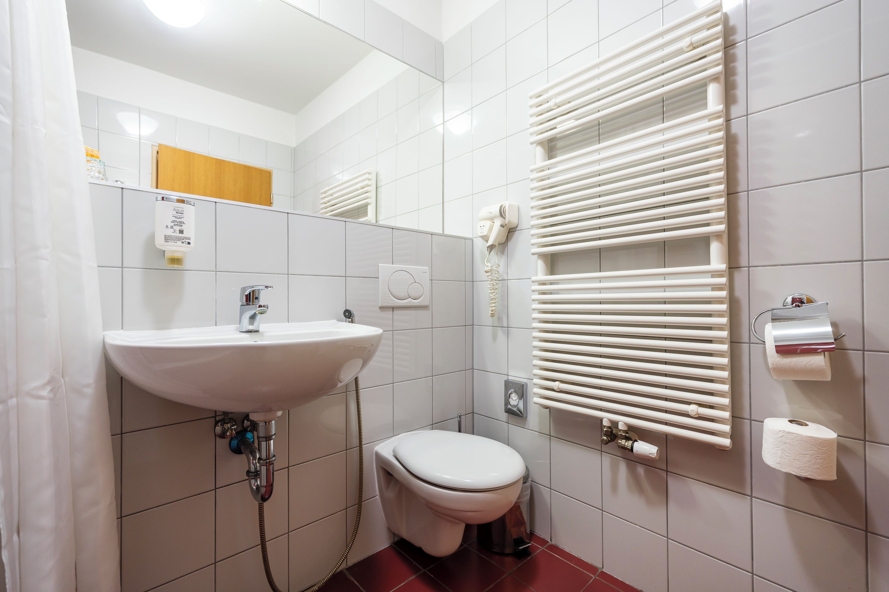 Casa de banho com lavatório, sanita e porta-toalhas.