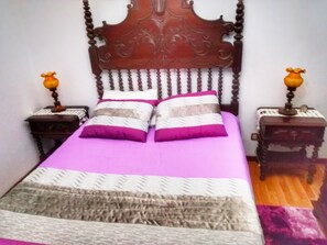 Una cama con cabecera de madera, dos mesitas de noche y una colcha estampada.