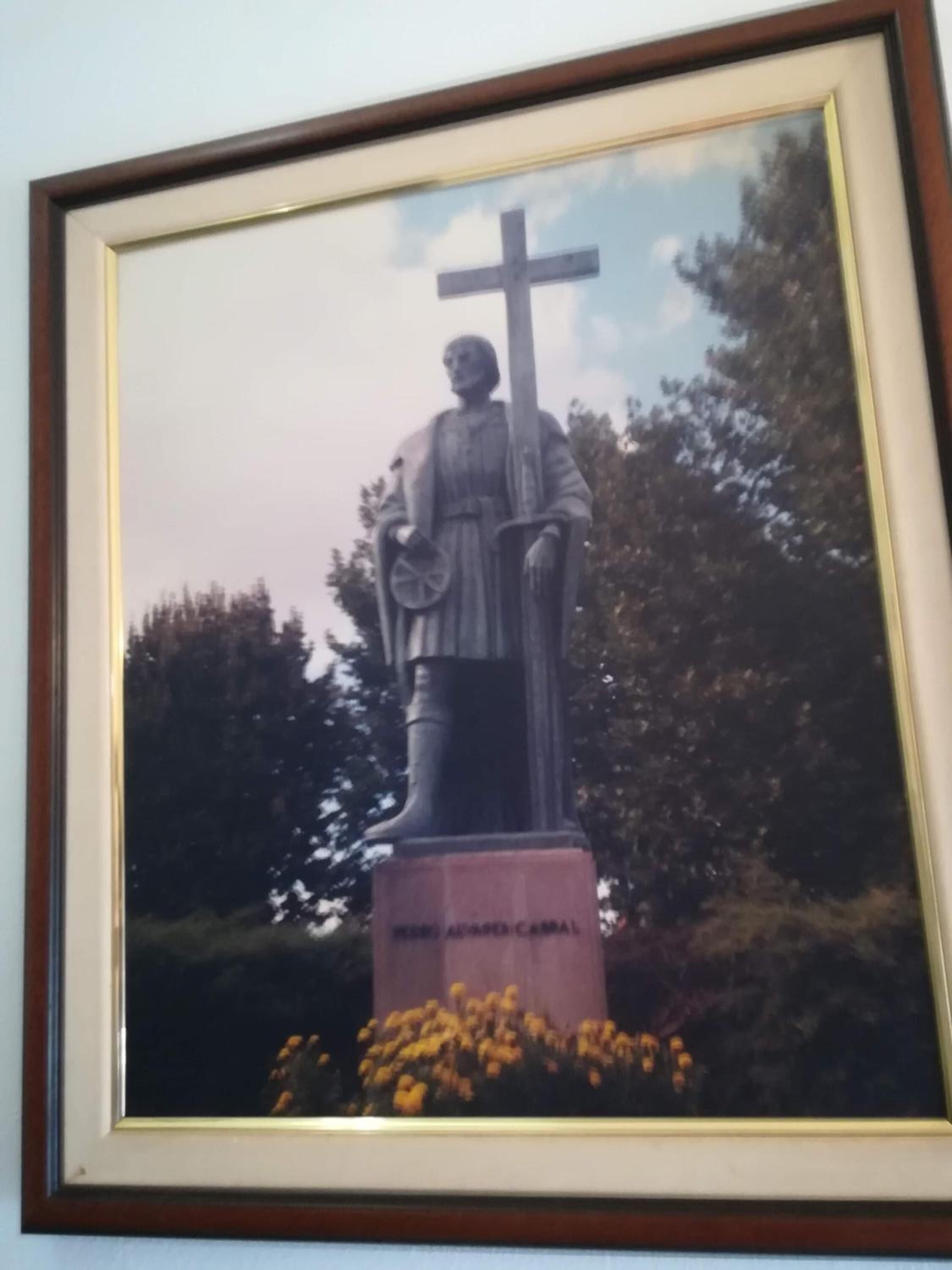 A framed photograph of a statue with a cross, a book, and a staff.