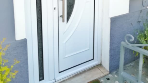 A white door with a keyhole and a handle, a wooden beam structure above, and a mailbox labeled "AL" to the right.