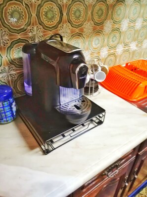 Una cafetera sobre una encimera de cocina con un salpicadero decorativo.