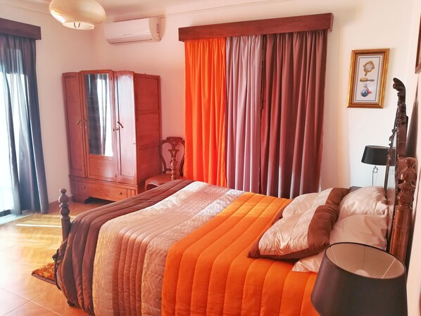 Un dormitorio con cama, armario, silla y mesita de noche.