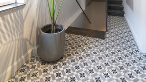 Ein Flur mit Topfpflanze, Treppe und strukturiertem Bodenbelag.