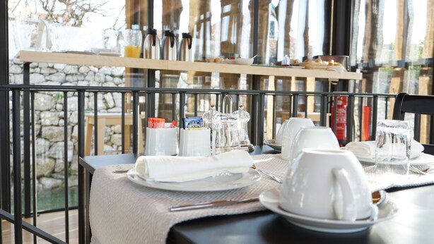 A breakfast table set with plates, cups, and a Nespresso machine. - Muralha Charm House (Lamego)