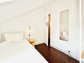 Une chambre à coucher avec un lit, une table de chevet et un miroir au mur.