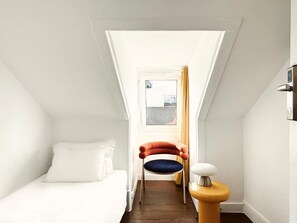 Une petite pièce comprenant un lit, une chaise et une petite table.