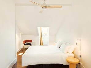 Une chambre à coucher avec un lit, un ventilateur de plafond, une table de chevet et une chaise.