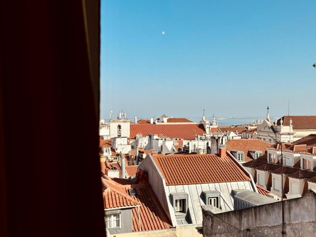 A cityscape with red-tiled rooftops and a clear sky.