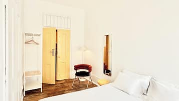 A bedroom with a bed, a chair, a wardrobe, a mirror, and a ceiling fan.
