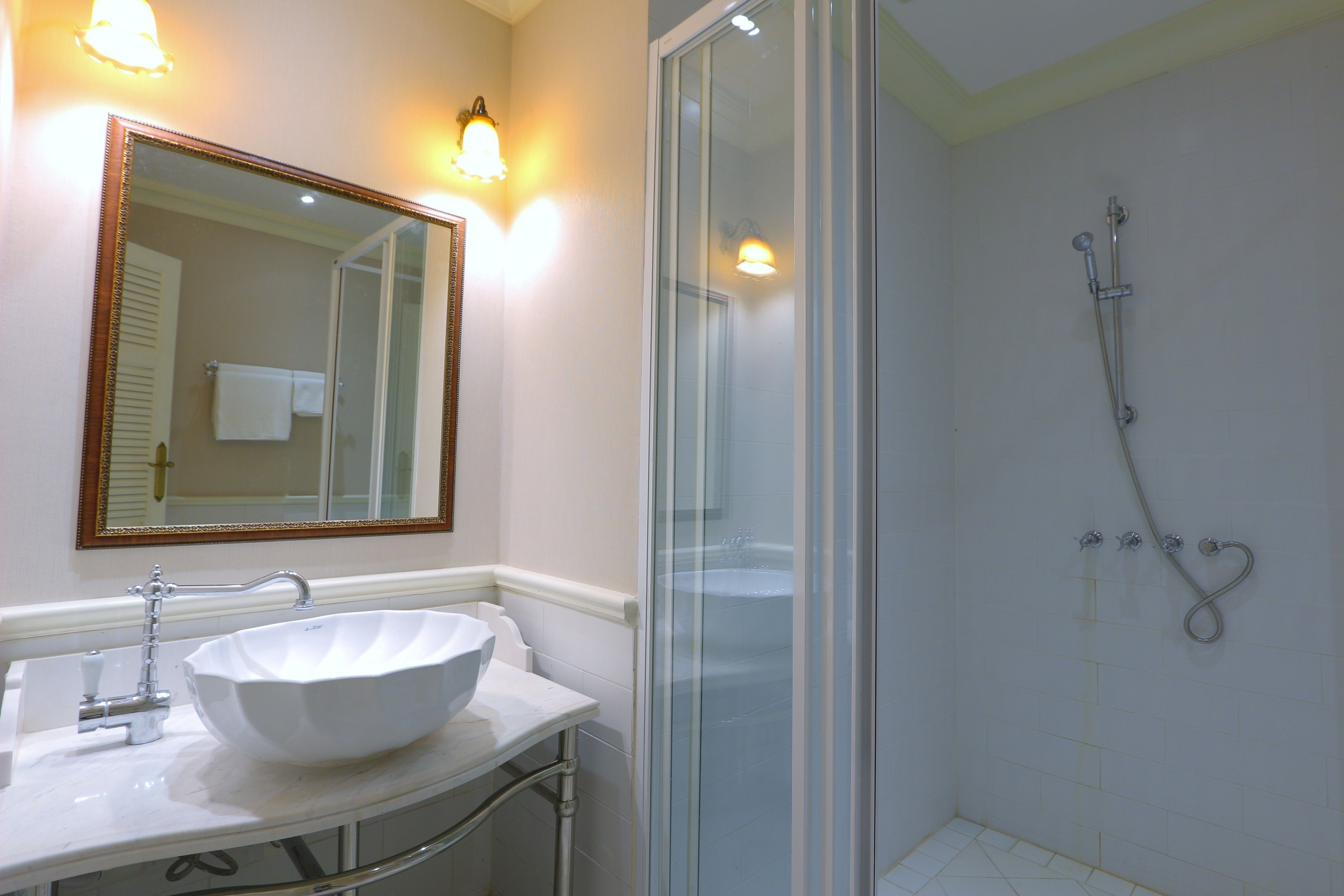 A bathroom with a white sink, a large mirror, and a glass-enclosed shower.