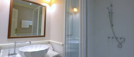 A bathroom with a white sink, a large mirror, and a glass-enclosed shower.