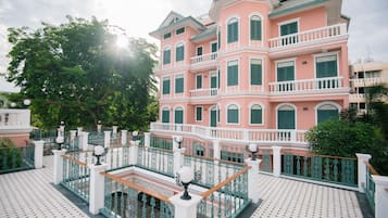 Un edificio rosa con balcones y piso de baldosas.