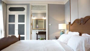 Camera d'albergo con un letto grande, una testiera in legno, un comodino con una lampada, una cassettiera e uno specchio.