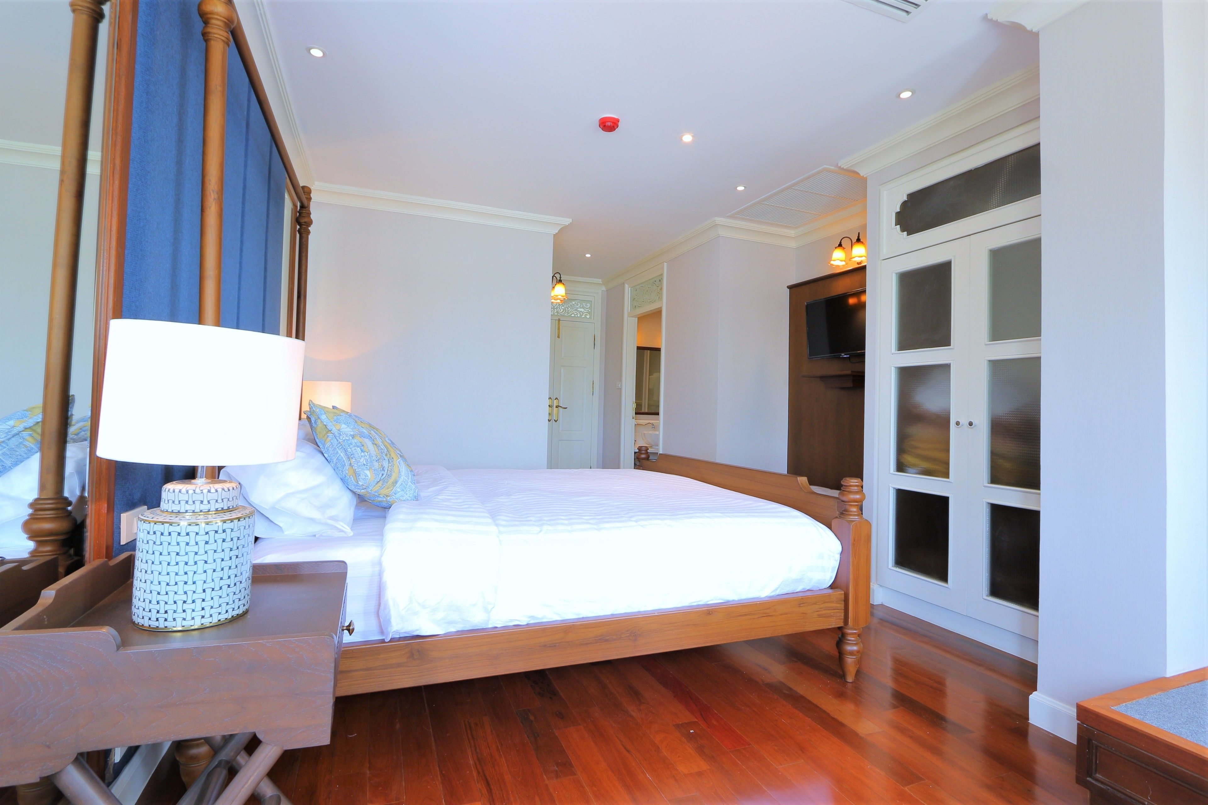 Une chambre à coucher avec un lit en bois, une table de chevet avec une lampe et une armoire aux portes en verre dépoli.