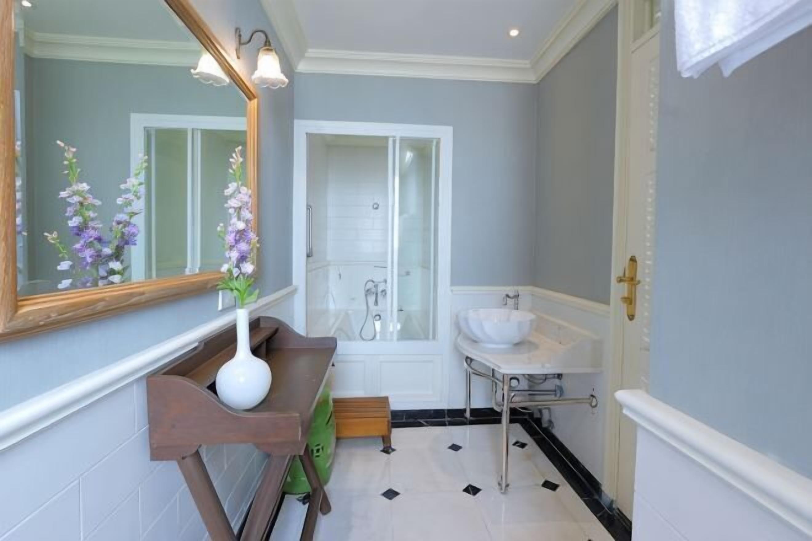 A bathroom with a mirror, sink, and shower.