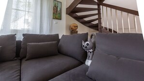 A modern living room with a dark grey sectional sofa, a wooden staircase, and a decorative globe on a wooden stand. - ApartView - Osada Zamkowa Pasym (Pasym)