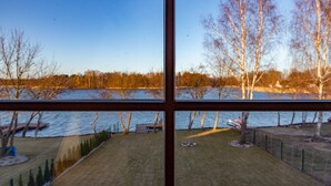 A view through a window of a backyard with a lawn, a small pond, and trees. - ApartView - Osada Zamkowa Pasym (Pasym)