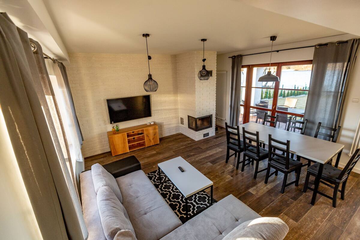 Ein modernes Wohnzimmer mit Sofa, Esstisch und Fernseher.