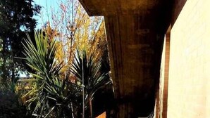 A narrow outdoor corridor with a tiled floor, a bamboo wall, and a white plastic chair. - Casa Claudia (Montecassiano)