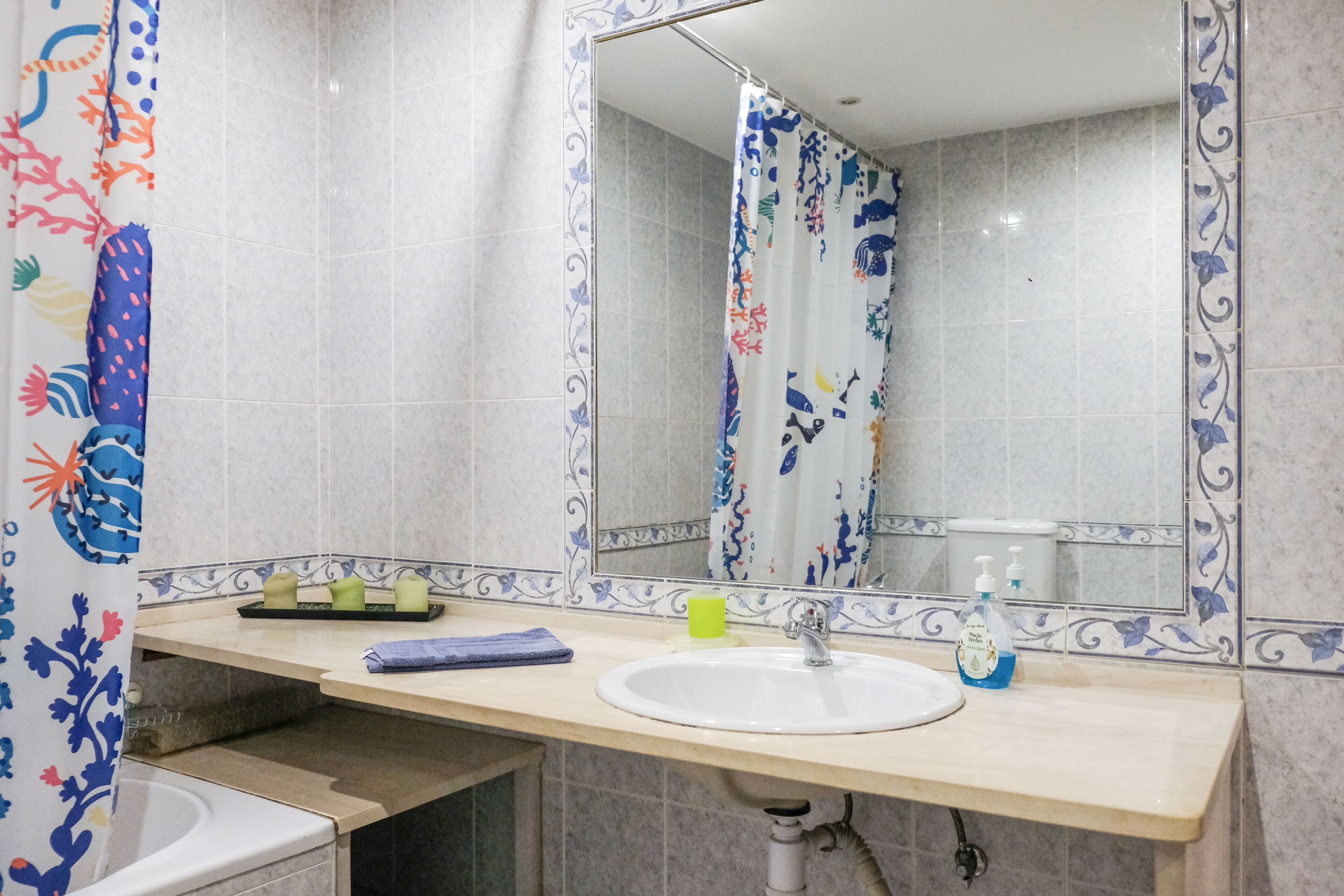A bathroom with a sink, mirror, and shower curtain.