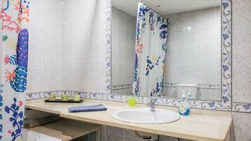 A bathroom with a sink, mirror, and shower curtain.